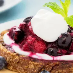 Fetta di pane integrale con yogurt greco, frutti di bosco e menta. Una deliziosa colazione con yogurt greco.