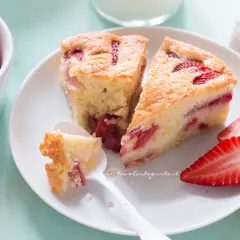 Fette di torta di fragole soffice e profumata, con fragole fresche e una cucchiaiata appena assaggiata.