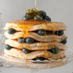 Pancake senza latte, una torre dorata con mirtilli freschi e sciroppo d'acero che cola.