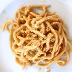 Un piatto di bigoli in salsa, pasta spessa condita con un sugo saporito e cosparsa di pangrattato tostato.