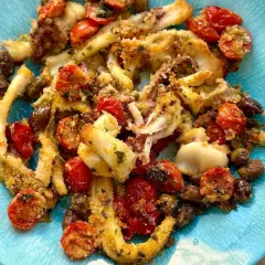 Calamari gratinati al forno con pomodorini e olive, un piatto saporito e croccante servito su un piatto blu.