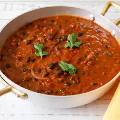 Un invitante piatto di fagioli alla messicana, con fagioli neri in una salsa rossa speziata, guarnito con coriandolo fresco.