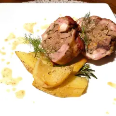 Coniglio in porchetta ripieno, servito con patate arrosto e salsa.