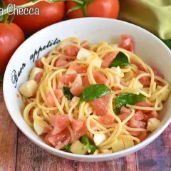 Un piatto di pasta alla checca con pomodori freschi, mozzarella e basilico, pronto per essere gustato.