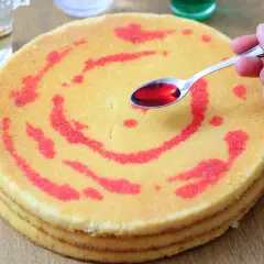 Mano versa sciroppo rosso su pan di spagna decorato.