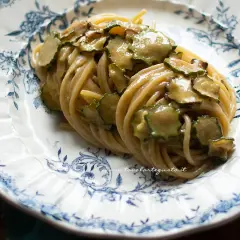 Spaghetti alla Nerano, un piatto cremoso con zucchine fresche, servito su un piatto decorato con motivi blu.