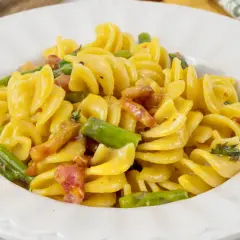 Fusilli cremosi con pancetta croccante e asparagi freschi, una deliziosa carbonara di asparagi.