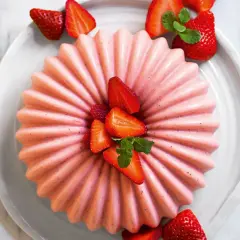 Delizioso bavarese alle fragole, decorato con fragole fresche e menta, su un piatto bianco.