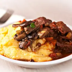 Polenta cremosa con spezzatino di manzo e funghi. Un classico piatto italiano, perfetto per scoprire polenta con cosa accompagnarla.