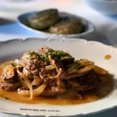 Fegato alla veneziana, un classico veneto, servito su un piatto bianco con cipolle caramellate e prezzemolo tritato.