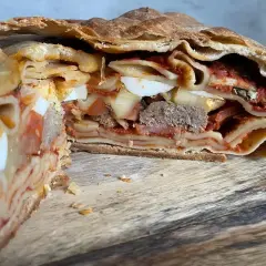 Fetta di timballo di pasta con strati di pasta, uova sode, ragù e carne, racchiuso in una crosta dorata.