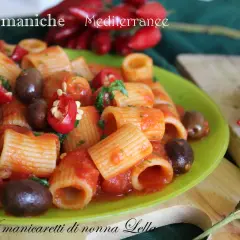 Piatto di pasta mezze maniche con pomodoro, olive e peperoncino, un classico della cucina mediterranea.
