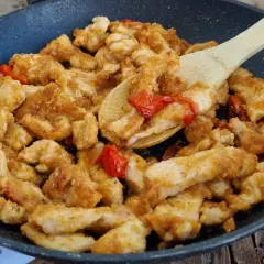 Straccetti di pollo dorati e saporiti in padella con pomodorini, pronti per essere gustati.