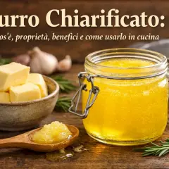 Burro chiarificato: cos'è, proprietà e benefici. Cubetti di burro in una ciotola, un vasetto di burro chiarificato dorato e una spiga di rosmarino su un tavolo di legno.