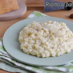 Un cremoso risotto alla parmigiana, guarnito con scaglie di formaggio, pronto per essere gustato.
