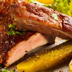 Succulente costine al forno, glassate e cotte alla perfezione, servite con cetriolini e insalata fresca.