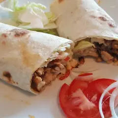 Due deliziosi kebab fatti in casa, ripieni di carne saporita, verdure fresche e serviti con pomodoro e cipolla.
