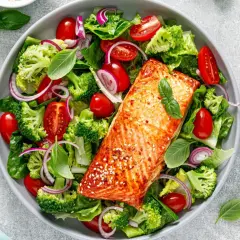 Insalata colorata con salmone alla griglia, broccoli, pomodorini e cipolla rossa. Un piatto gustoso e leggero, ideale per chi cerca cibi senza carboidrati.
