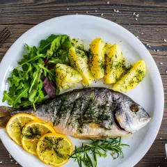 Orata in padella, cotta alla perfezione, servita con patate, limone e insalata fresca. Un piatto delizioso e salutare.