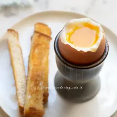 Un perfetto uovo alla coque con tuorlo dorato, servito con croccanti toast.