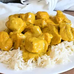 Piatto di riso basmati con saporito pollo al curry, ricoperto da una cremosa salsa gialla.