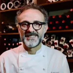 Un sorriso tra gli scaffali di bottiglie di vino, un ritratto di uno dei tanti chef stellati italiani che rendono la cucina italiana famosa nel mondo.