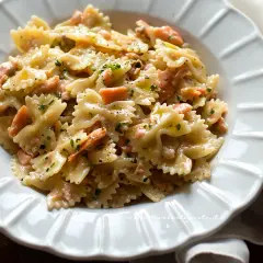 Farfalle cremose con pezzetti di salmone e prezzemolo tritato, un piatto invitante di pasta al salmone.
