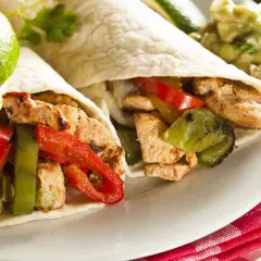 Due fajitas di pollo con peperoni, cipolle e guacamole. Un piatto saporito e colorato, pronto per essere gustato.