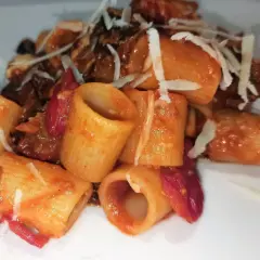 Mezze maniche alla norma con melanzane fritte, pomodoro e ricotta salata grattugiata. Un piatto siciliano gustoso.