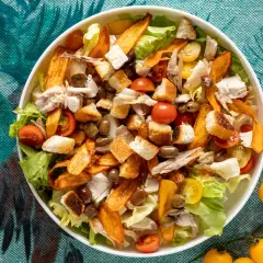 Insalata di pollo ricca con crostini, pomodorini, olive e patate dolci croccanti. Un piatto gustoso e colorato.