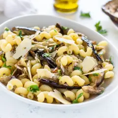 Piatto di pasta con melanzane in bianco, condita con scaglie di parmigiano e prezzemolo fresco.
