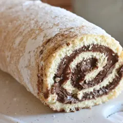 Un soffice rotolo alla Nutella, cosparso di zucchero a velo, pronto per essere gustato.
