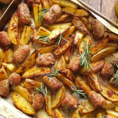 Salsiccia e patate al forno, dorate e profumate al rosmarino, su una teglia. Un piatto rustico e invitante.