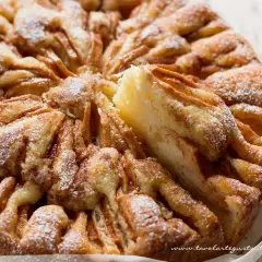 Una deliziosa torta di mele, cosparsa di zucchero a velo, con una fetta rimossa che rivela la morbida consistenza.