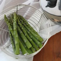 Asparagi freschi in un cestello metallico pronti per essere cotti nella pentola a pressione.