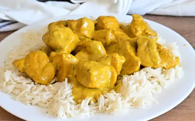 Piatto di riso basmati con saporito pollo al curry, ricoperto da una cremosa salsa gialla.