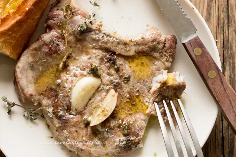 Braciole di maiale succulente, condite con aglio e erbe aromatiche, pronte per essere gustate con pane croccante.