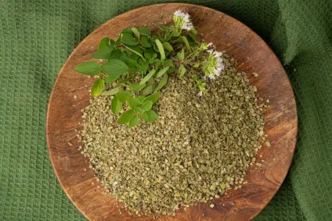 Un piatto di legno con maggiorana essiccata e fresca, pronta per insaporire ogni piatto in cucina.