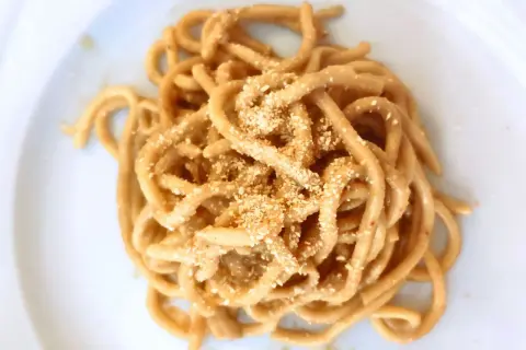 Un piatto di bigoli in salsa, pasta spessa condita con un sugo saporito e cosparsa di pangrattato tostato.