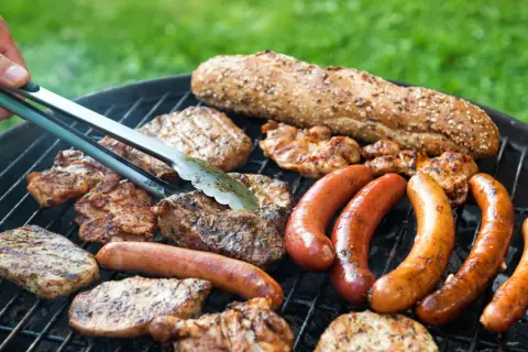 Grigliata con tante salsicce e bistecche, pane rustico e pollo. La carne da fare alla brace è pronta per essere gustata.