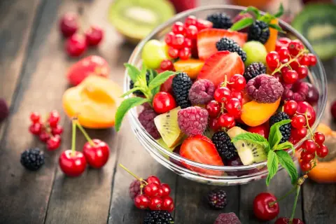 Ciotola di frutta fresca e colorata, con fragole, lamponi, ribes, more e kiwi, un'ottima scelta di frutta con meno zuccheri.