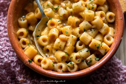 Un piatto fumante di pasta e fagioli in scatola, arricchito da prezzemolo fresco, pronto per essere gustato.