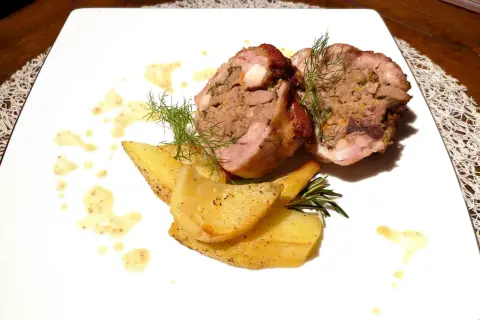 Coniglio in porchetta ripieno, servito con patate arrosto e salsa.