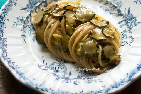 Spaghetti alla Nerano, un piatto cremoso con zucchine fresche, servito su un piatto decorato con motivi blu.