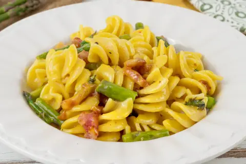 Fusilli cremosi con pancetta croccante e asparagi freschi, una deliziosa carbonara di asparagi.