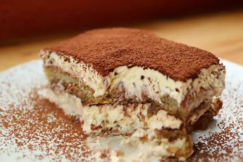 Una fetta di tiramisù, soffice e cremosa, cosparsa di cacao. Perfetta per un momento di dolcezza, anche in gravidanza.