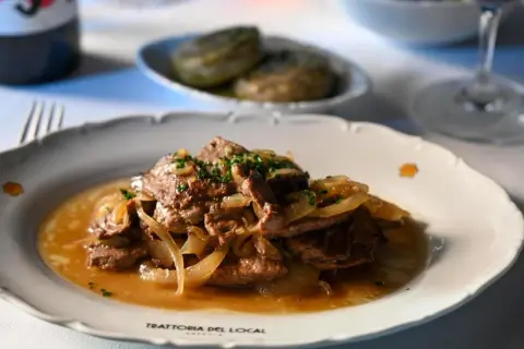 Fegato alla veneziana, un classico veneto, servito su un piatto bianco con cipolle caramellate e prezzemolo tritato.
