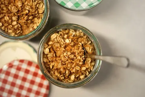 Un cucchiaino affonda in un vasetto pieno di fiocchi d'avena e cannella, pronti per essere gustati. Ecco come mangiare i fiocchi d'avena per una colazione sana.