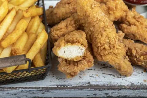 Straccetti di pollo impanati croccanti e patatine fritte dorate, un classico per un pasto gustoso.