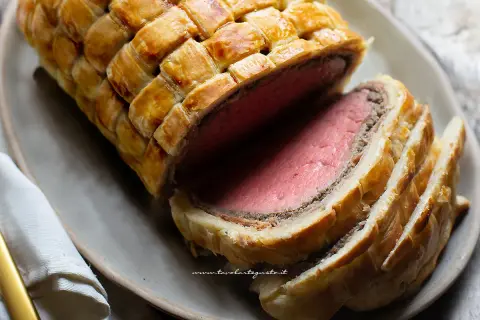 Un succulento filetto alla Wellington, cotto alla perfezione e avvolto in pasta sfoglia dorata, pronto per essere gustato.